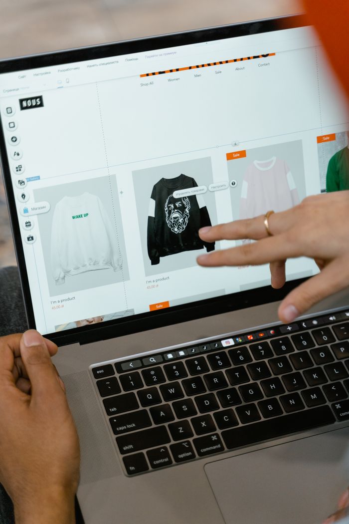 our-story Close-up of hands interacting with a shopping website on a laptop screen indoors.
